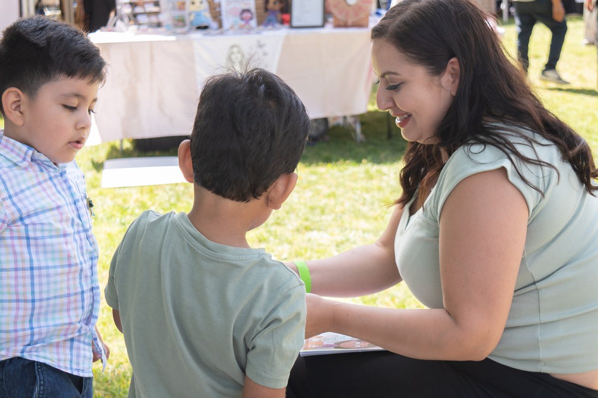 Denise reading her book with two young boys at a community event